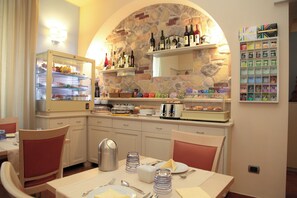 A dining area with a stone wall, a buffet with various food items, and a selection of wine bottles.