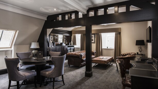 A spacious living area with a high ceiling, a round table with chairs, a sofa, and a piano. - The Vermont ApartHotel (Newcastle-upon-Tyne)