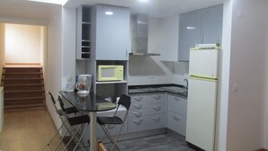 Una cocina compacta con una mesa de comedor, sillas, microondas, estufa y refrigerador.