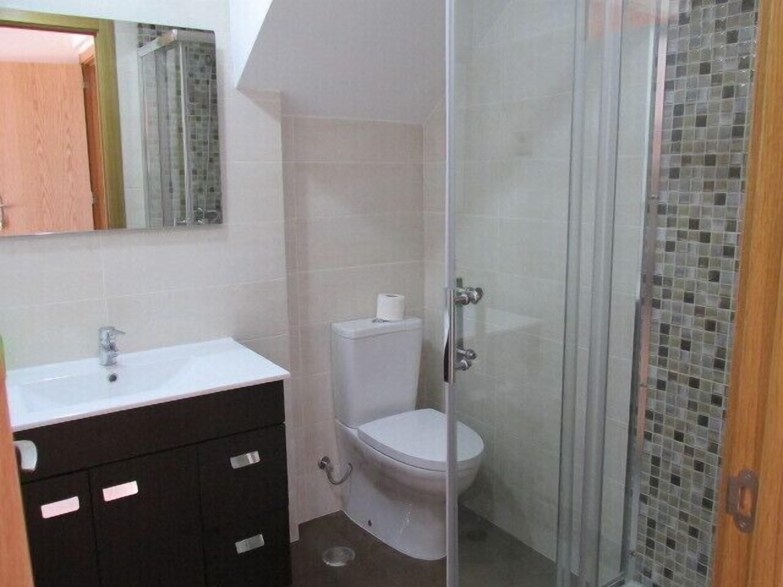 A bathroom with a white sink, a toilet, and a glass shower enclosure.