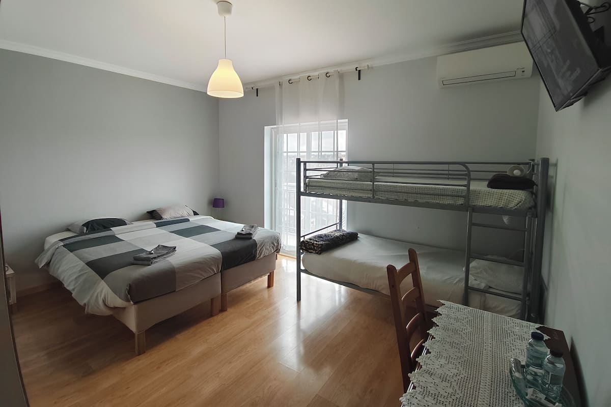A compact room with a bunk bed, a single bed, and a small table with water bottles.