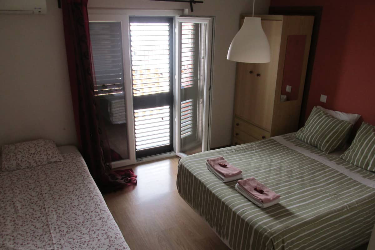 A bedroom with a bed, a wardrobe, a sliding glass door, and a hanging light fixture.
