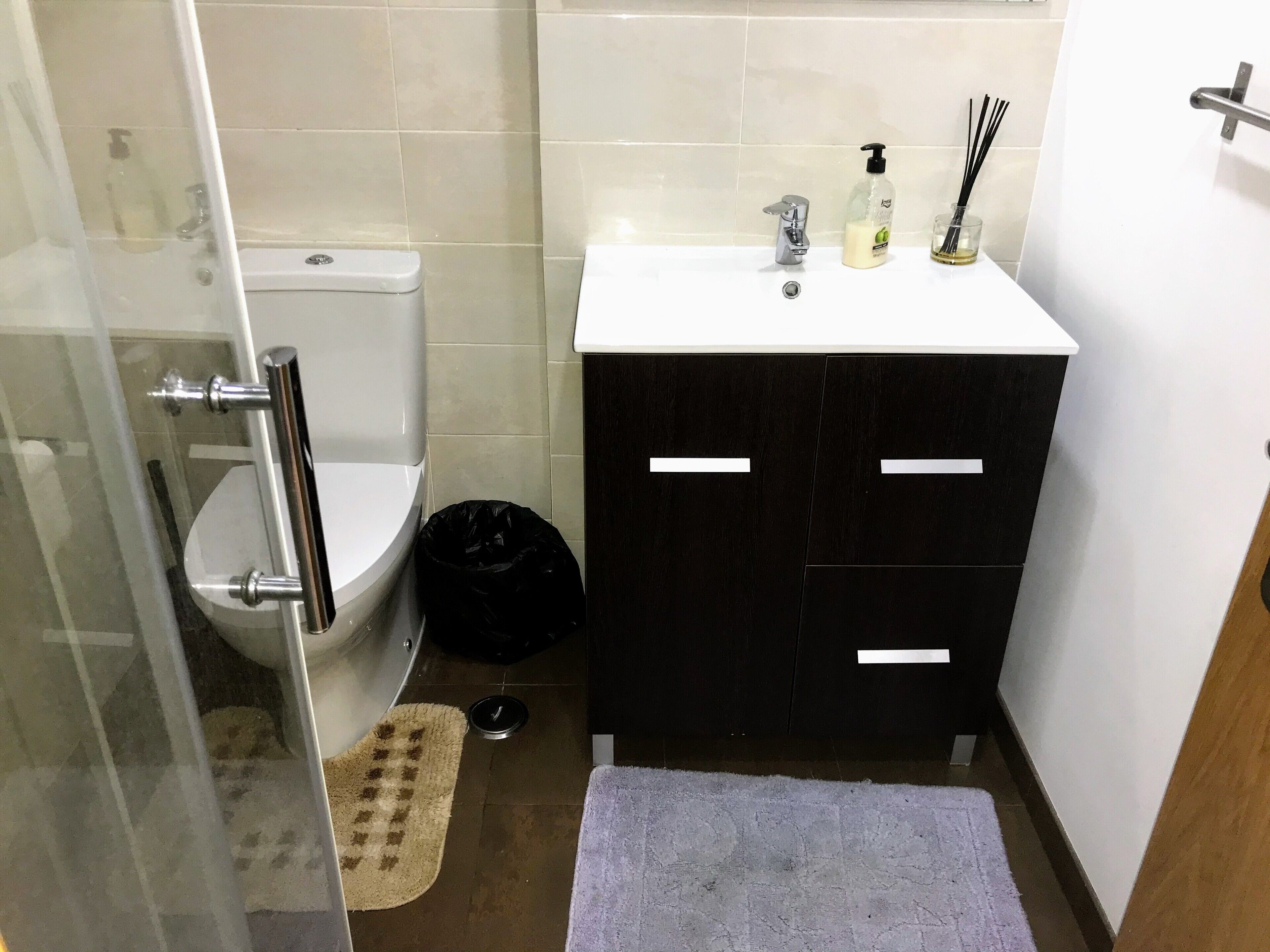 Et badeværelse med toilet, vask og et sort skab.