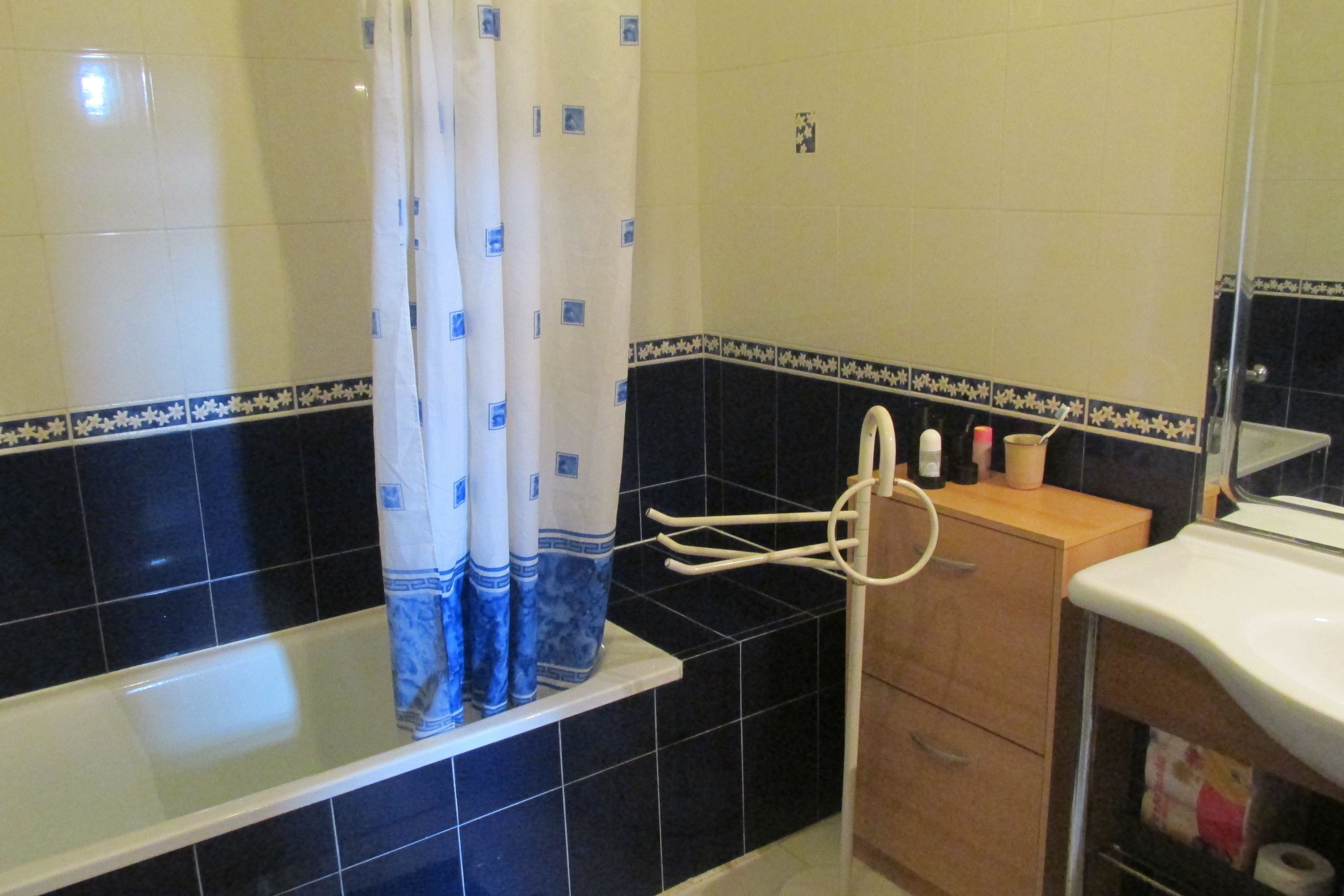 A bathroom with a bathtub, a shower curtain, a towel rack, a wooden cabinet, and a mirror.