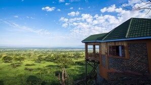 A wooden cabin with a green roof overlooking a vast landscape.