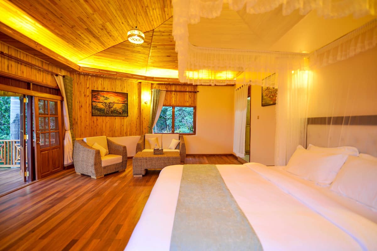 A wooden-floored bedroom with a bed, two sofas, and a painting on the wall.