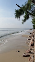 A beach with a rocky shoreline and waves gently lapping at the sand.
