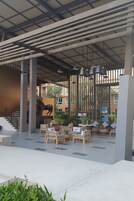 A covered outdoor seating area with wooden chairs and tables, a staircase, and a decorative horse statue.
