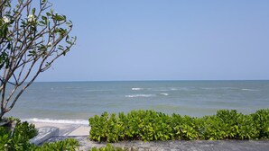 A beach view with a clear sky, ocean waves, and a pathway leading to the water.