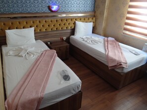 A hotel room with two beds, a wooden headboard, a nightstand, and a wall-mounted light fixture. - Meta Hotel (Bursa)