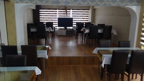 A dining area with tables and chairs, a television screen, and patterned wall decorations. - Meta Hotel (Bursa)