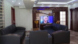A modern living room with two black leather sofas, a coffee table, and a flat-screen TV. - Meta Hotel (Bursa)