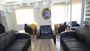 A modern lobby with leather sofas, a wooden coffee table, and decorative vases. - Meta Hotel (Bursa)