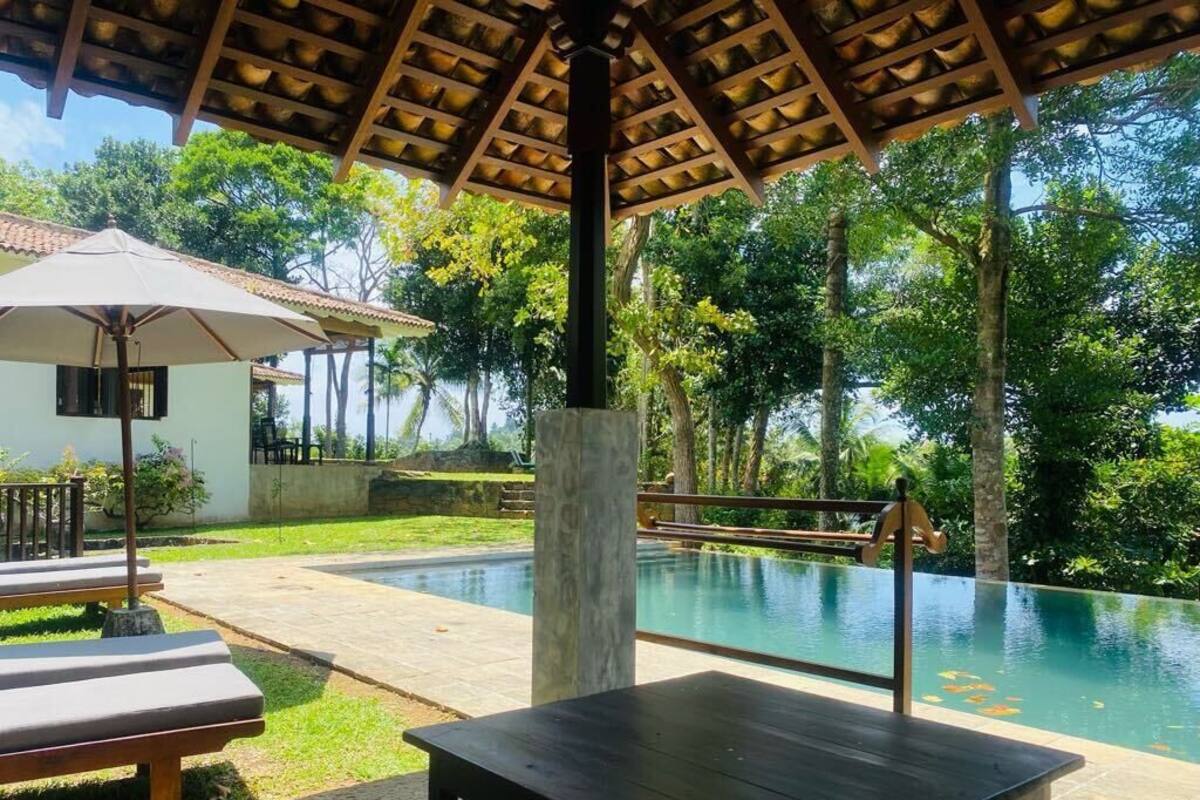 An outdoor pool area with a wooden pergola, lounge chairs, and a table.