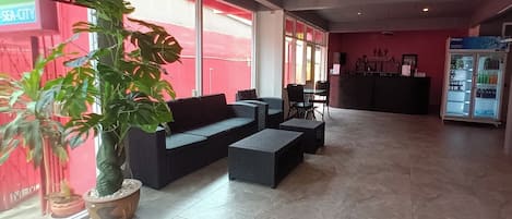 A spacious lobby with a large potted plant, a sofa, and a seating area.