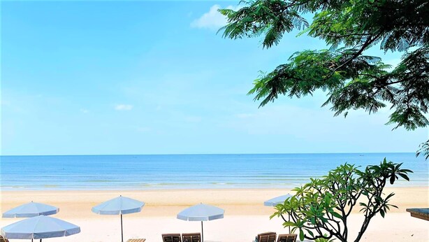 Un espacio de relax frente al mar con sillones de playa y sombrillas.