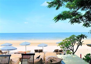 Un espacio de relax frente al mar con sillones de playa y sombrillas.