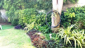 Un jardín con diversas plantas, un árbol y un aro decorativo.