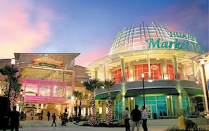 Shop and dine in style at HUAHUN Market Village, a modern shopping destination with outdoor seating areas and lush surroundings.