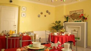 A dining area with red tablecloths, a white dog figurine, and a fireplace.