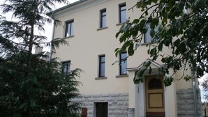 A multi-story building with a beige facade, stone base, and a central entrance with a door.