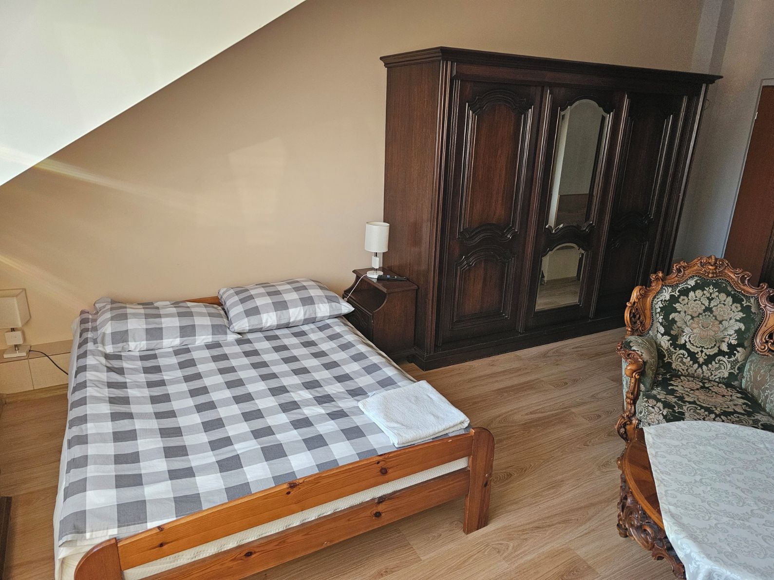 Une chambre à coucher avec un lit en bois, une table de chevet, une commode et une chaise.