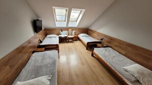 Un dormitorio con cuatro literas de madera, un escritorio, dos sillas y dos tragaluces.