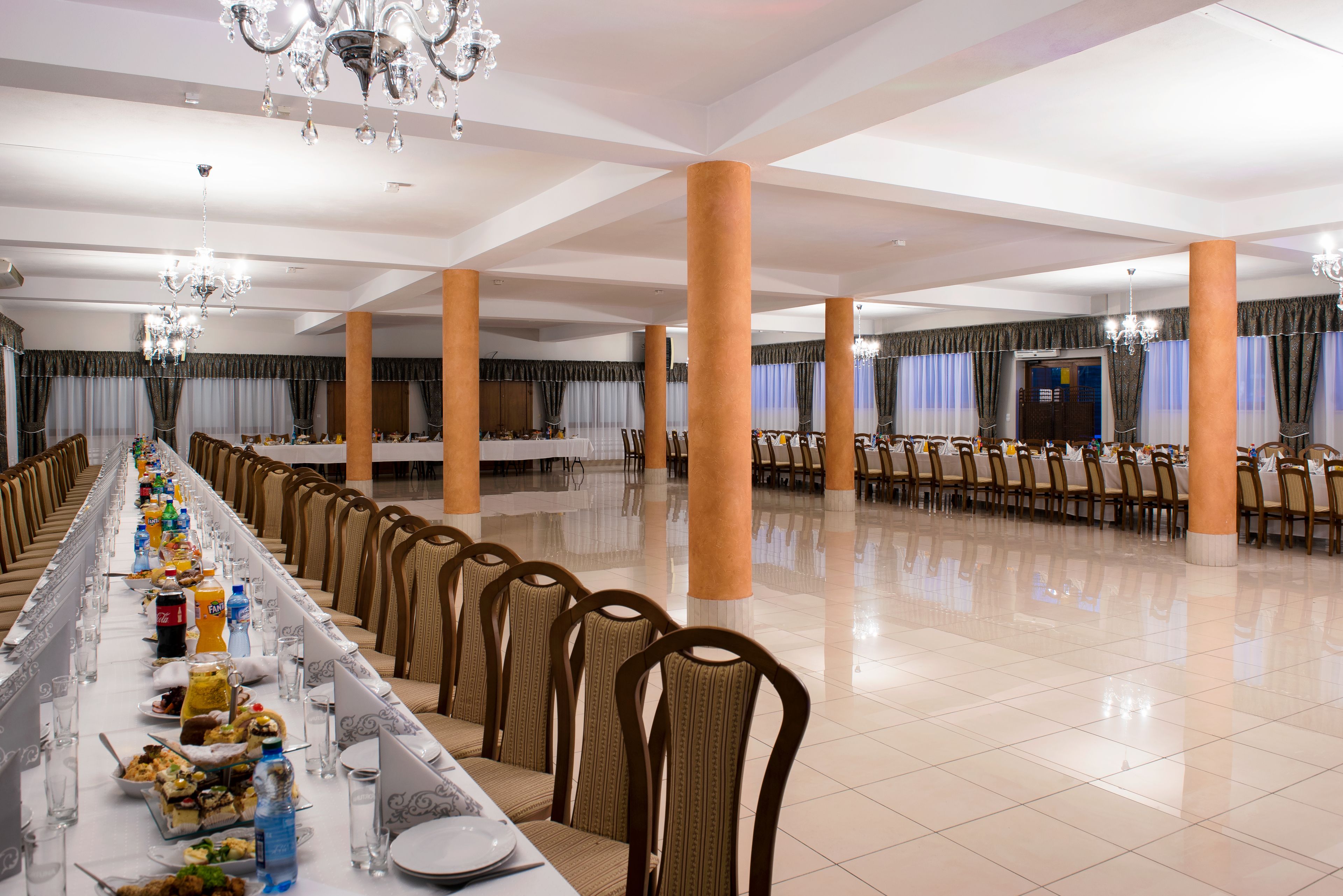 Un salón de banquetes con mesas largas, sillas y candelabros.