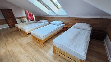 A room with three wooden beds, a wooden wardrobe, and a skylight.