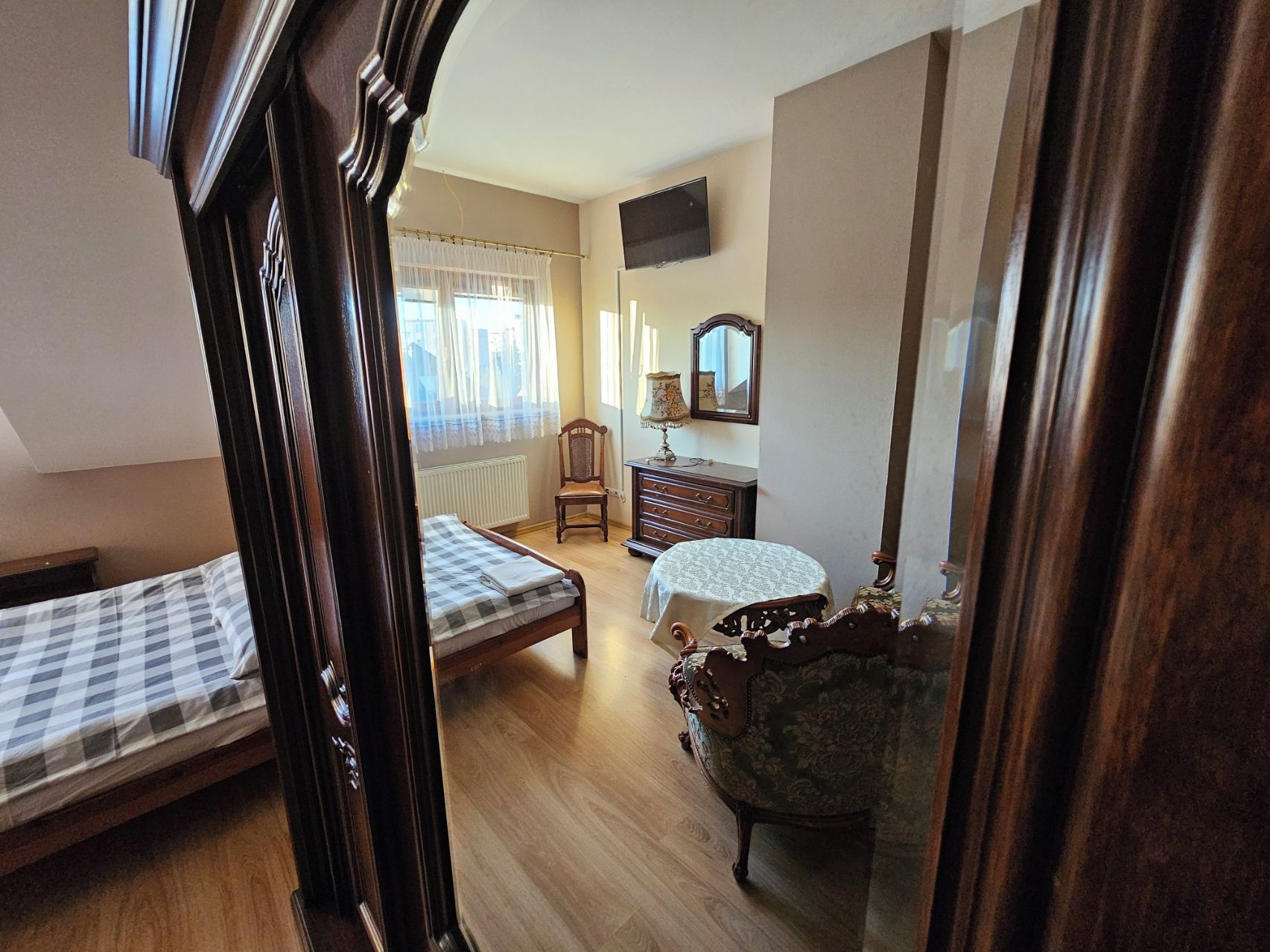 A room with two beds, a dresser, a chair, a mirror, and a television.