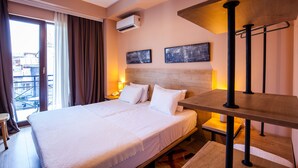 Ein Hotelzimmer mit einem großen Bett, einem Nachttisch aus Holz, einem Tisch und Blick auf die Stadt durch das Fenster.