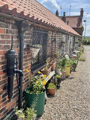 A brick building with a tiled roof, outdoor seating, and potted plants. - OYO Yarm Cottages (Yarm)