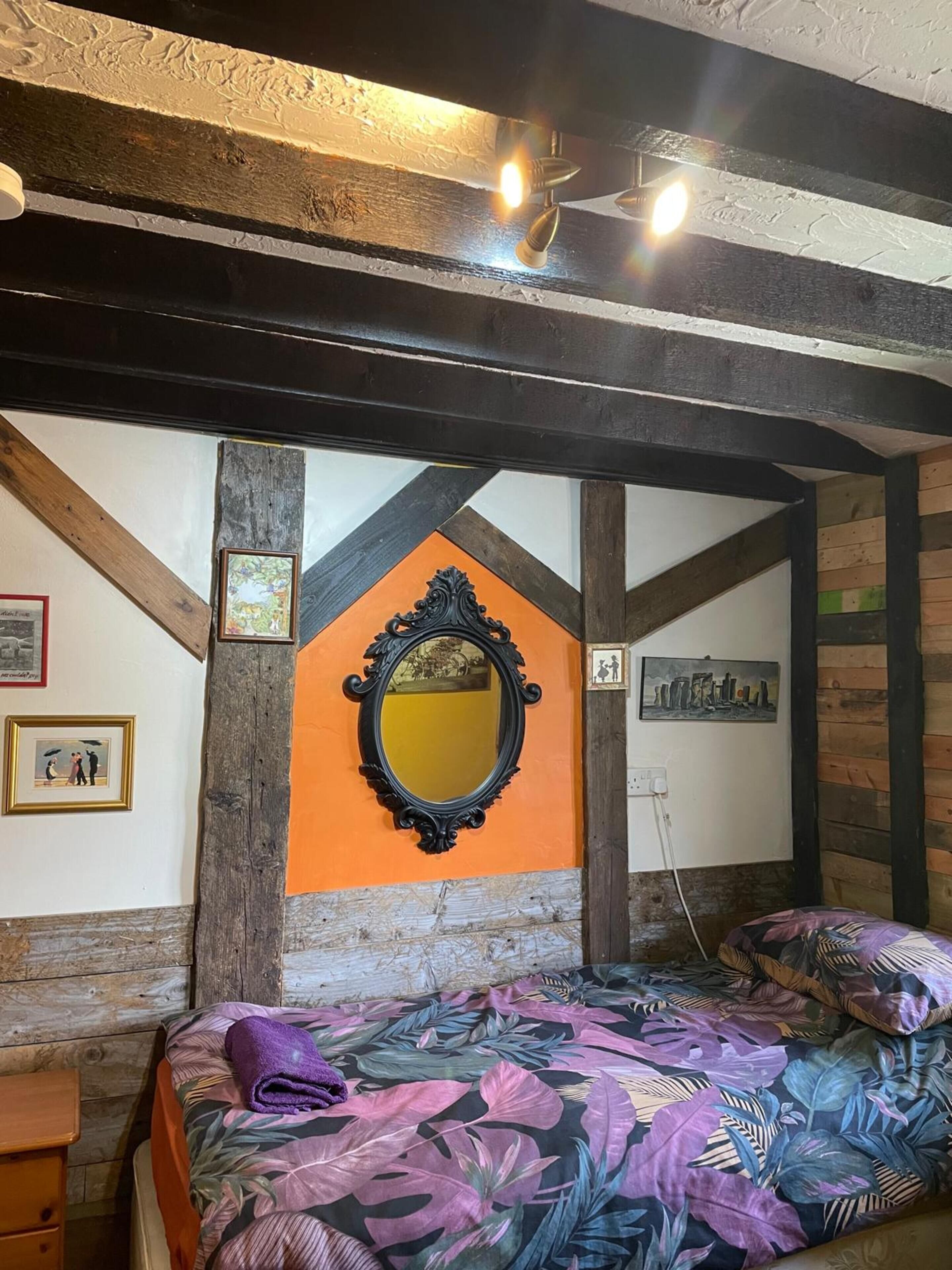 A bedroom with a bed, a mirror, and wooden beams.
