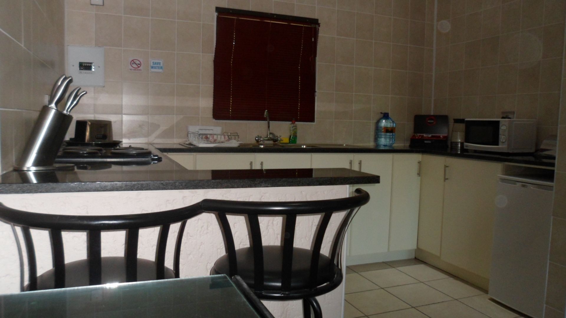 A kitchen with a bar area, a microwave, a sink, and a refrigerator.
