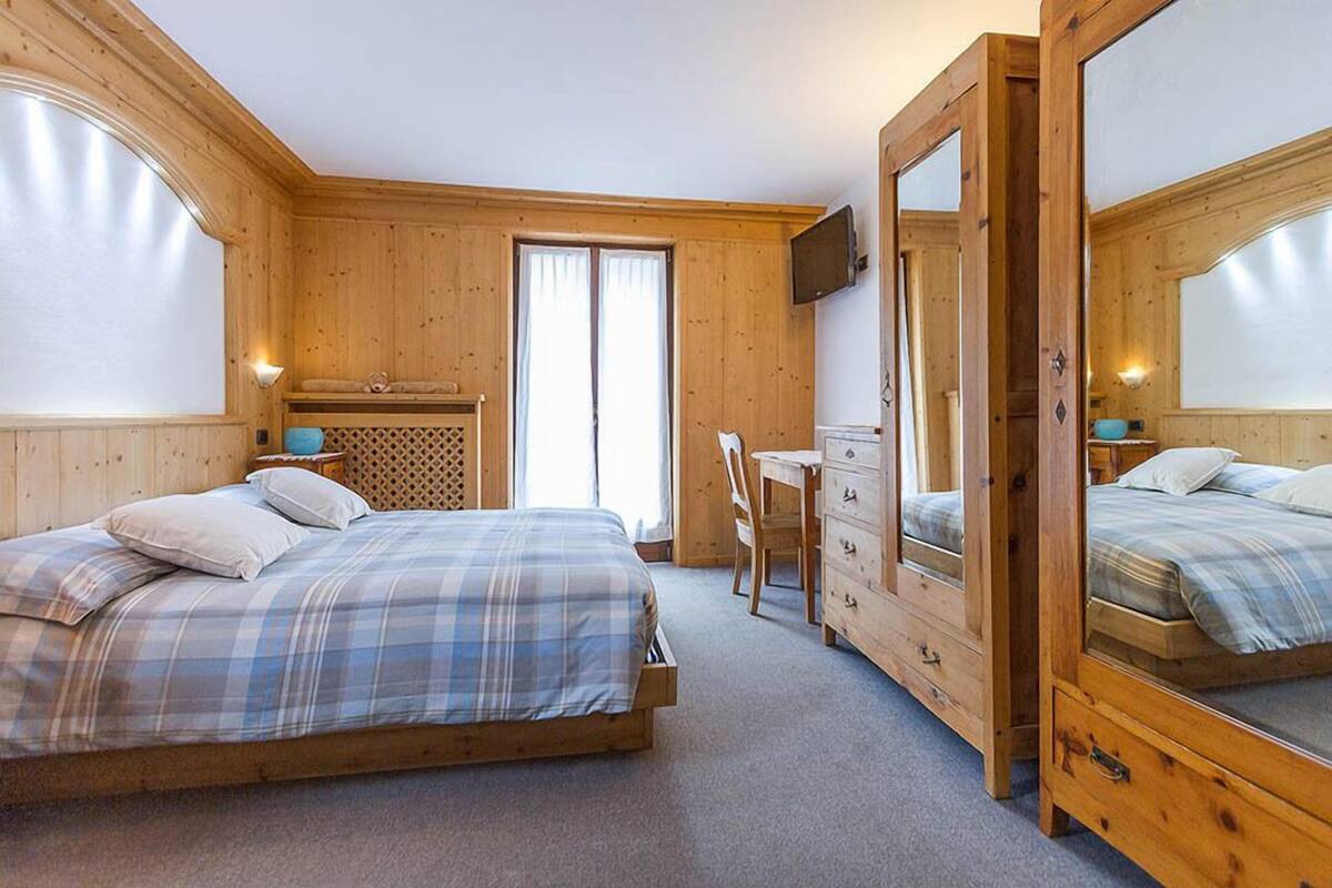 A bedroom with a bed, a desk, a chair, and a mirror.