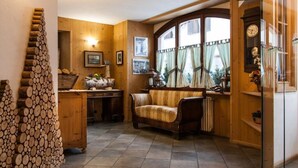 A cozy room with a wooden interior, a sofa, a radiator, and a window with curtains. - Hotel Compagnoni (Valfurva)
