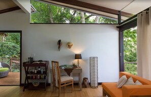 A modern living room with a wooden floor, a sofa, a dining table with chairs, a lamp, and a decorative wall piece. - Isla Palenque Member of the Cayuga Collection (Boca Chica)