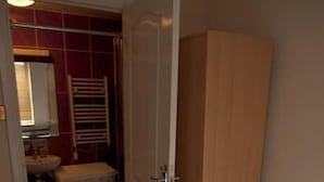 Une chambre à coucher comprenant un lit, une armoire, un lave-linge et une salle de bain visible à travers une porte ouverte.