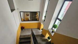 A staircase with a yellow wall and a black railing, leading to an upper floor. - Hotel Antigone (Tirana)