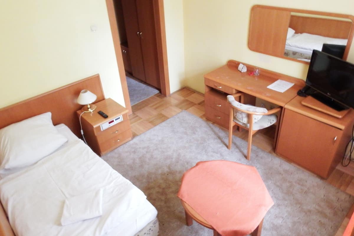 Habitación de hotel con cama, escritorio, silla, mesita, televisión y armario.