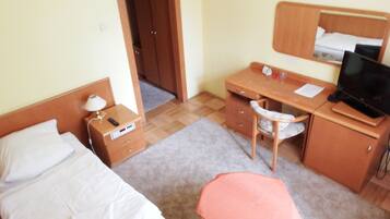 Une chambre d’hôtel équipée d’un lit, d’un bureau, d’une chaise, d’une petite table, d’un téléviseur et d’une armoire.