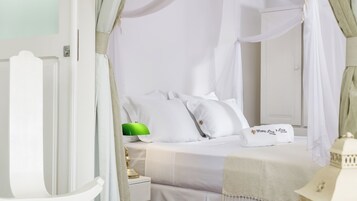 Un dormitorio con cama de dosel, ropa de cama blanca y una lámpara verde.