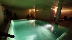 An indoor swimming pool with a water fountain feature, surrounded by walls and a few potted plants. - La Senda de los Enebros (Higuera de las Duenas)