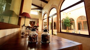 A wooden table with glass jars containing dried flowers, a red lamp, and a view of a courtyard through arched windows. - La Senda de los Enebros (Higuera de las Duenas)
