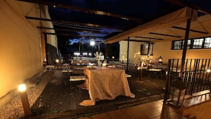 An outdoor patio area with tables and chairs, a covered seating area, and a view of the night sky. - La Senda de los Enebros (Higuera de las Duenas)