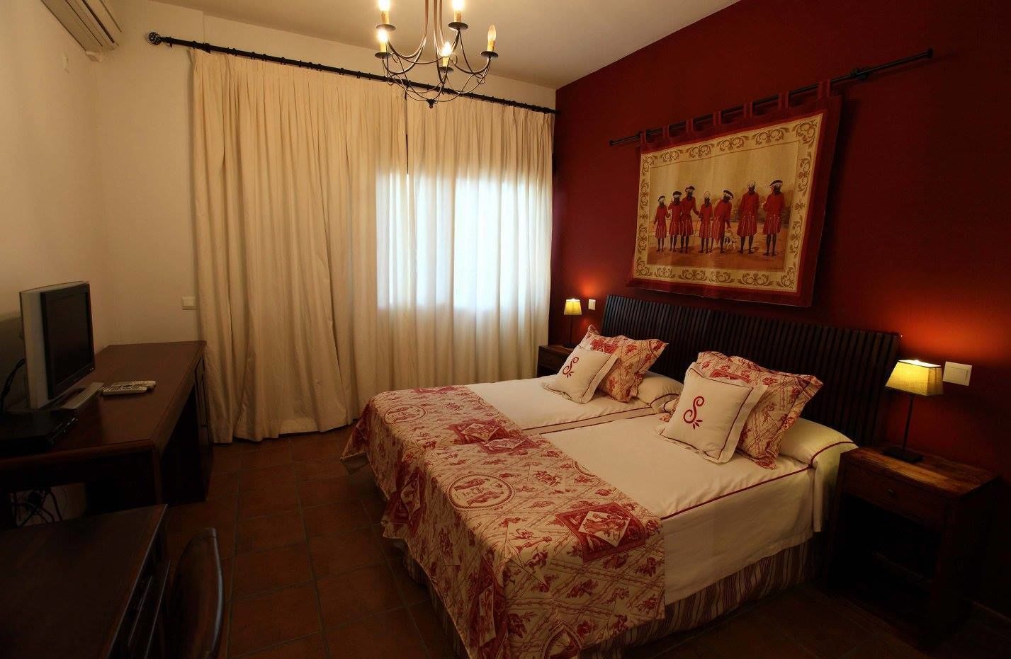 Une chambre d’hôtel avec un grand lit, un bureau avec un ordinateur, une télévision et un tableau au mur.