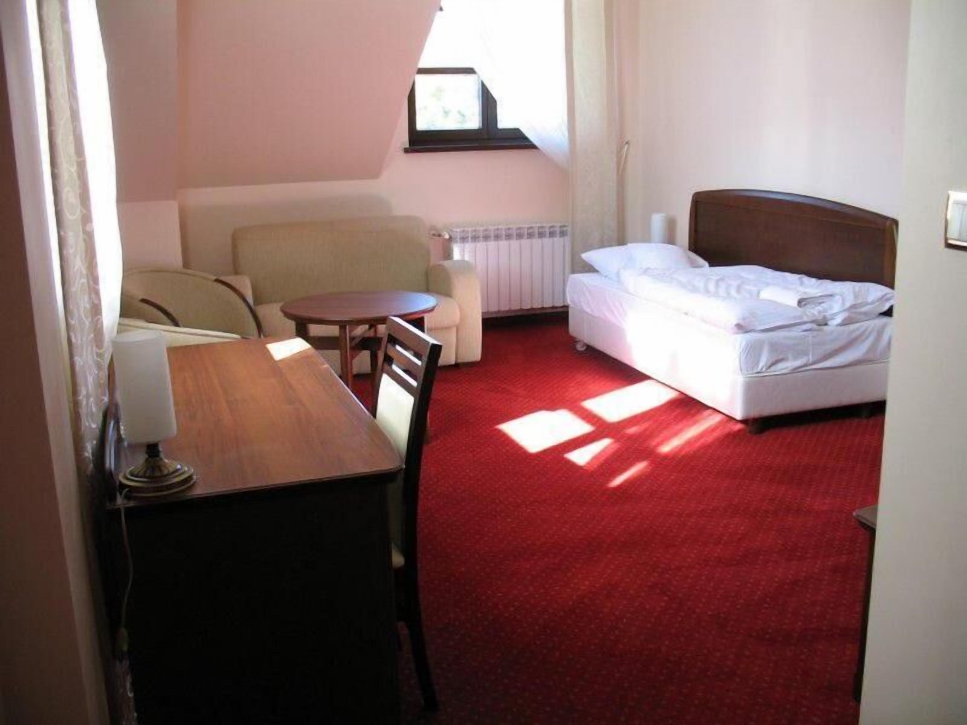 Een hotelkamer met een bed, een klein rond tafeltje, een stoel en een bank.