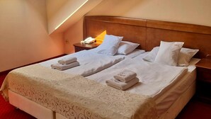 A hotel room with a bed, a nightstand, a lamp, and a skylight.