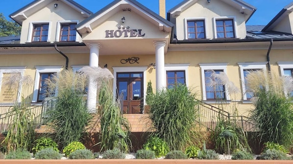 A hotel with a central entrance, columns, and a sign above the door.