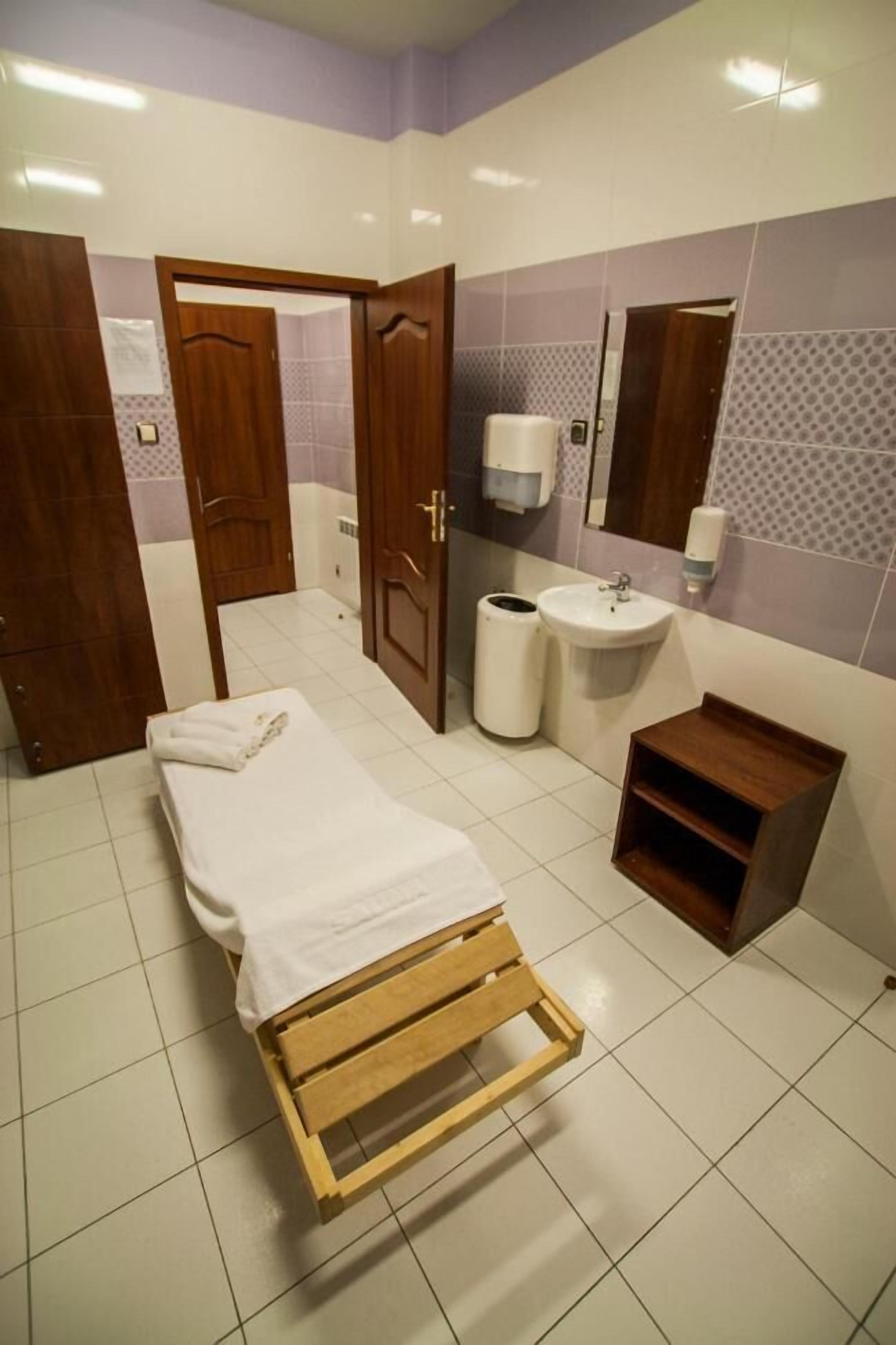 A small, clean room with a bed, a sink, and a mirror.